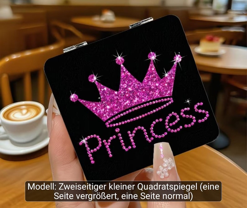 Puede incluir: Un espejo de bolsillo cuadrado con fondo negro que presenta un gr&aacute;fico de corona rosa brillante y la palabra Princess en letras rosas. El espejo tiene una bisagra de metal plateado y es un modelo de doble cara con un lado de aumento.