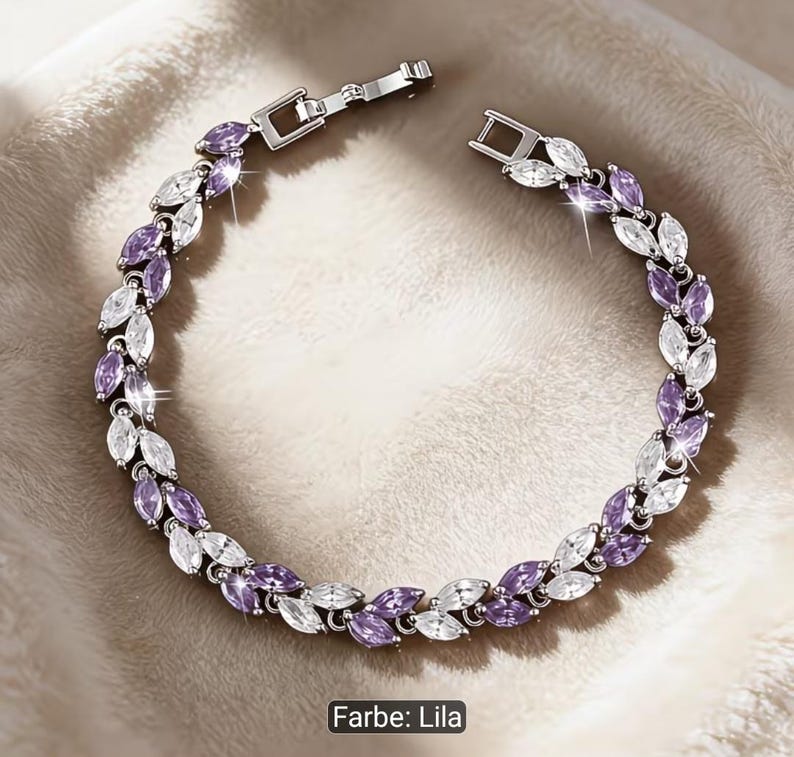 Puede incluir: Una pulsera de tono plateado con un patr&oacute;n repetitivo de piedras de corte marquesa en colores alternos morado claro y blanco transparente. La pieza de joyer&iacute;a incluye un cierre de metal y est&aacute; dispuesta en forma circular sobre una superficie.