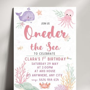 Może przedstawiać: Zaproszenie w stylu akwareli na pierwsze urodziny z napisem "Oneder the Sea". Projekt zawiera ilustracje fioletowego wieloryba, różowej ośmiornicy, rozgwiazd, żółwia i koralowców. Zaproszenie zawiera datę, godzinę, miejsce i informacje RSVP.