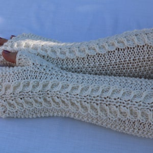 May include: A pair of white knitted fingerless gloves with a cable knit pattern.