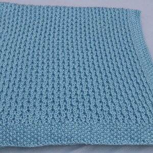 May include: A light blue knitted baby blanket with a textured stitch pattern.
