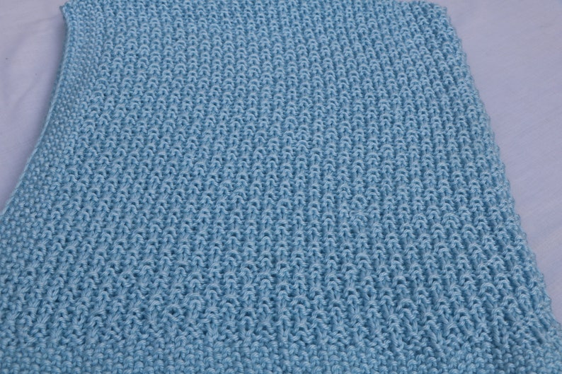 May include: A light blue knitted blanket with a textured pattern.