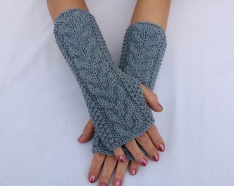 May include: A pair of gray knitted fingerless gloves with a cable knit design. The gloves are displayed on a white background, showcasing the intricate texture and pattern. The gloves are designed to cover the hand and wrist.