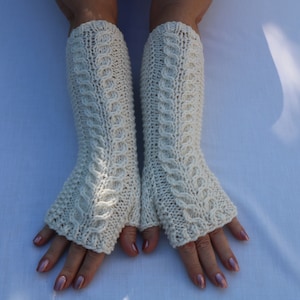 May include: A pair of off-white fingerless gloves with a cable knit pattern.