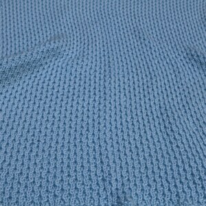 May include: A light blue knitted vest with a textured pattern.