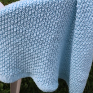 May include: A light blue knitted baby blanket with a textured stitch pattern.