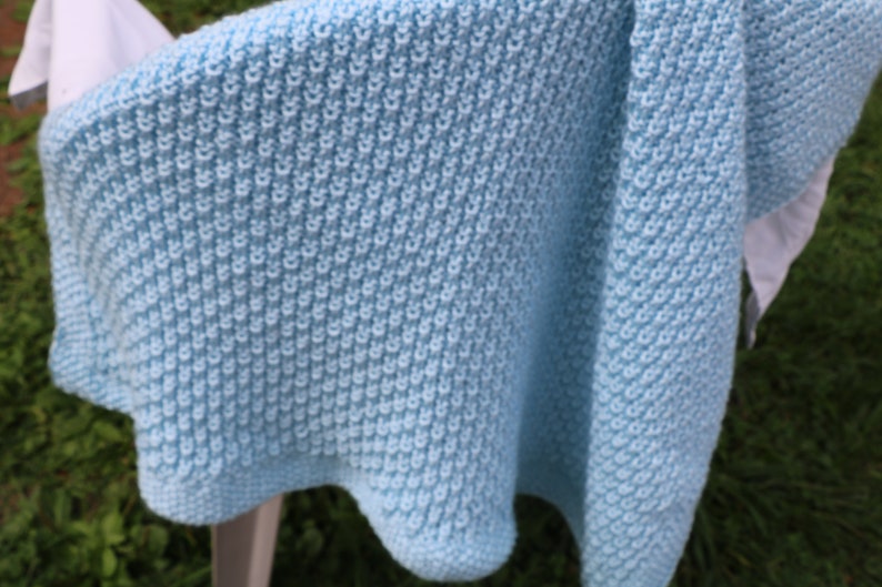 May include: A light blue knitted baby blanket with a textured stitch pattern.