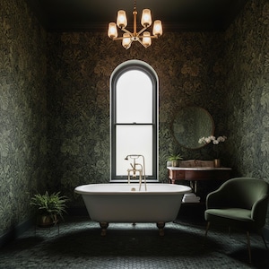 May include: A white clawfoot bathtub with gold-toned hardware sits in a bathroom featuring dark green botanical wallpaper, a round mirror, a wooden vanity, a green upholstered chair, a potted fern, and a six-light brass chandelier overhead.