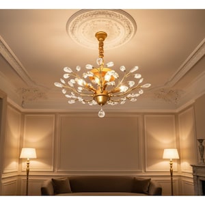 May include: A gold chandelier with crystal accents hangs from a white ceiling medallion. The chandelier has multiple lights and crystal leaf-shaped ornaments. The room features a sofa, lamps, and decorative wall panels, creating an elegant interior.
