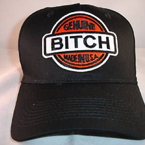 May include: Black baseball cap with an orange and white embroidered patch that says "Genuine Bitch Made in U.S.A."