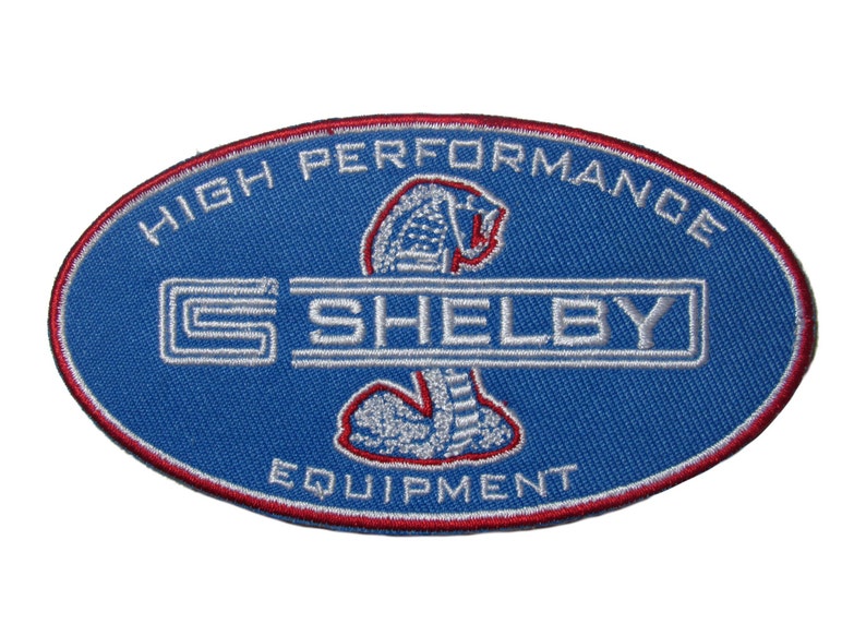 May include: A blue oval embroidered patch with the words "High Performance Shelby Equipment" and a white cobra logo.