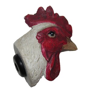 May include: A white rooster head with a red comb and wattle. The rooster head is a decorative piece with a black base.