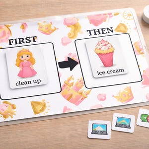 以下が含まれることがあります： ピンクと白のプリンセスをテーマにした教育用アクティビティセット。 「clean up」や「ice cream」などのイラストとテキストが書かれたカードが含まれています。追加のカードやアクセサリーが散らばっています。