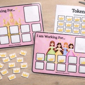 以下が含まれることがあります： 「I am Working For...」の文字と、お城とプリンセスのイラストが描かれたピンク色の報酬チャート。王冠型のトークンと、切り抜くためのトークンシートが含まれています。チャートにはトークンのスペースがあります。