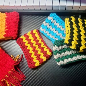 Puede incluir: Una colección de artículos rectangulares de ganchillo con varias combinaciones de colores, incluyendo rojo y amarillo, azul y gris, negro y amarillo, y verde y gris. Los artículos muestran un patrón de puntos repetitivo y texturizado.