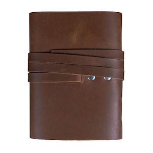 May include: A brown leather journal with a wrap-around strap closure. The journal is rectangular and features a textured surface. Two silver rivets secure the strap. The leather has a rich, warm tone.