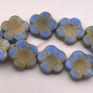 Könnte beinhalten: Eine Reihe von blauen und braunen Glasperlen in Blumenform. Die Perlen sind in Form von fünfblättrigen Blumen mit einer erhabenen Mitte.