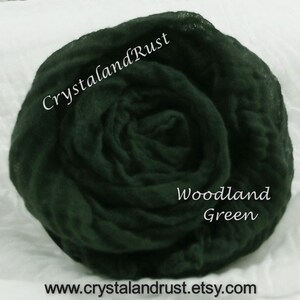 May include: A dark green, crinkled fabric backdrop, also known as a photography backdrop, for use in photography. The fabric is gathered in a rose-like shape. The text "Woodland Green" is written on the fabric. The text "CrystalandRust" is written on the fabric.