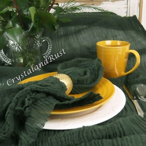 May include: A dark green, crinkled fabric table runner with a yellow mug and a gold napkin ring. The table runner is on a white wooden table with a bouquet of orange roses in a glass vase. The text "CrystalandRust" is visible on the table runner. The text "www.crystalandrust.etsy.com" is visible on the table runner.