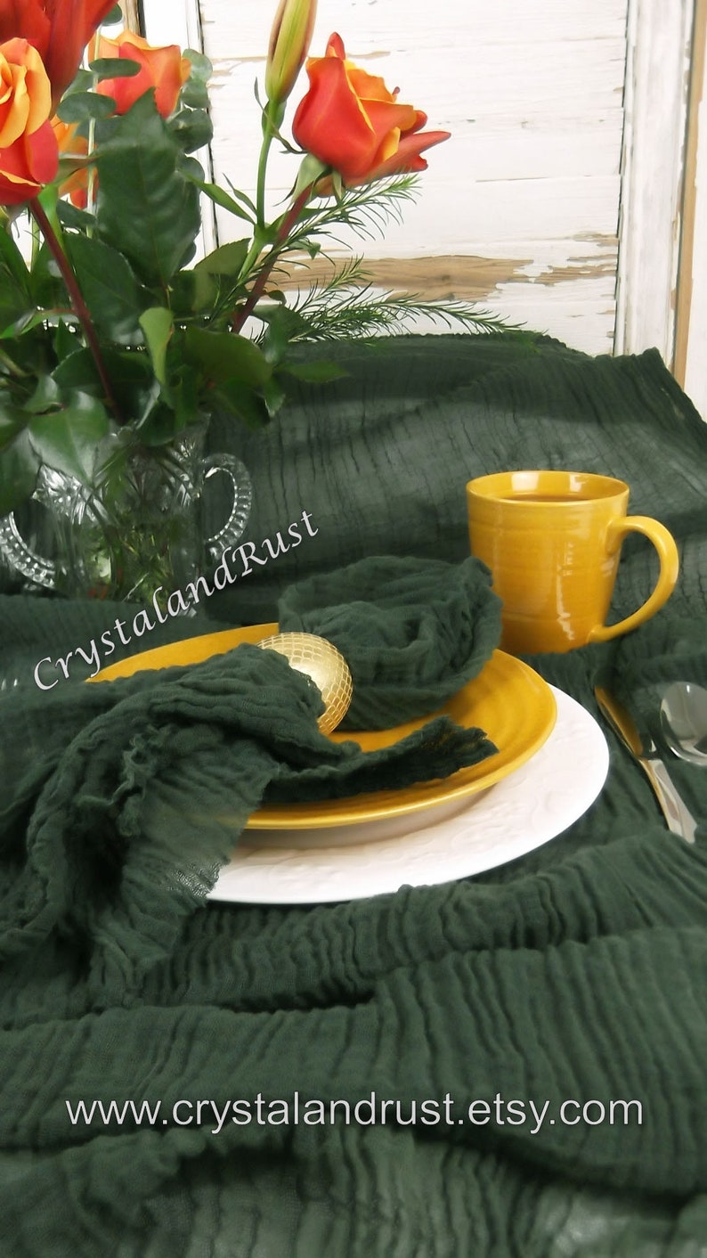May include: A dark green, crinkled fabric table runner with a yellow mug and a gold napkin ring. The table runner is on a white wooden table with a bouquet of orange roses in a glass vase. The text "CrystalandRust" is visible on the table runner. The text "www.crystalandrust.etsy.com" is visible on the table runner.