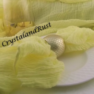 May include: A still-life image featuring a pale yellow, crinkled fabric draped over a white plate. A gold napkin ring and a glass are also present. The text "CrystalandRust" and website address are visible.
