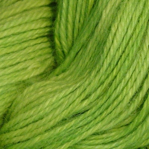 May include: A close-up of a skein of bright green yarn. The yarn is soft and fluffy, and it has a slightly textured surface.