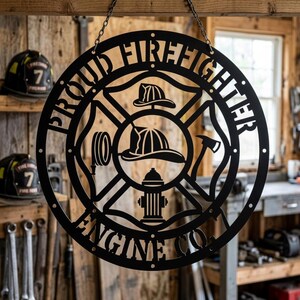 Może przedstawiać: Czarny metalowy znak z wyciętymi słowami "PROUD FIREFIGHTER ENGINE CO" w okrągłym wzorze. Znak przedstawia hełm strażacki, topór, wąż strażacki i hydrant. Znak wisi na łańcuchu.