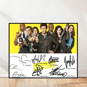 Può includere: Un poster incorniciato con il cast di Brooklyn Nine-Nine su uno sfondo giallo e bianco. Il poster include il titolo dello show e le firme dei membri del cast. Il cast è in una foto di gruppo, con gli attori in varie pose.