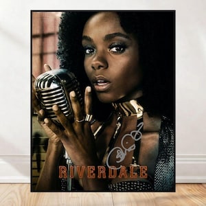 May include: A framed poster featuring a woman with dark hair holding a vintage microphone. She wears a gold choker and rings. The poster has the word "RIVERDALE" in brown text at the bottom, with an autograph.