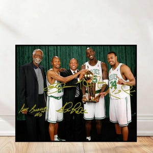 May include: A framed photograph featuring five men, including a man holding a trophy. The men are wearing suits and basketball jerseys. The jerseys are white with green accents. The photograph is signed in gold ink.