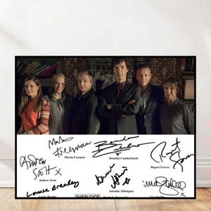 Puede incluir: Un póster enmarcado con un grupo de seis personas, probablemente actores, con sus firmas debajo. Los actores están en una habitación con una estantería al fondo. Las firmas incluyen a Benedict Cumberbatch y Martin Freeman.