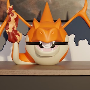 Op de afbeelding: Een gestileerd oranje en crèmekleurig wezenfiguur met grote vleugels, een puntige kop en een vlamvormige staart. Het wezen heeft een open mond met witte tanden en een cirkelvormig midden, met donkerblauwe vleugelmembranen en oranje randen.