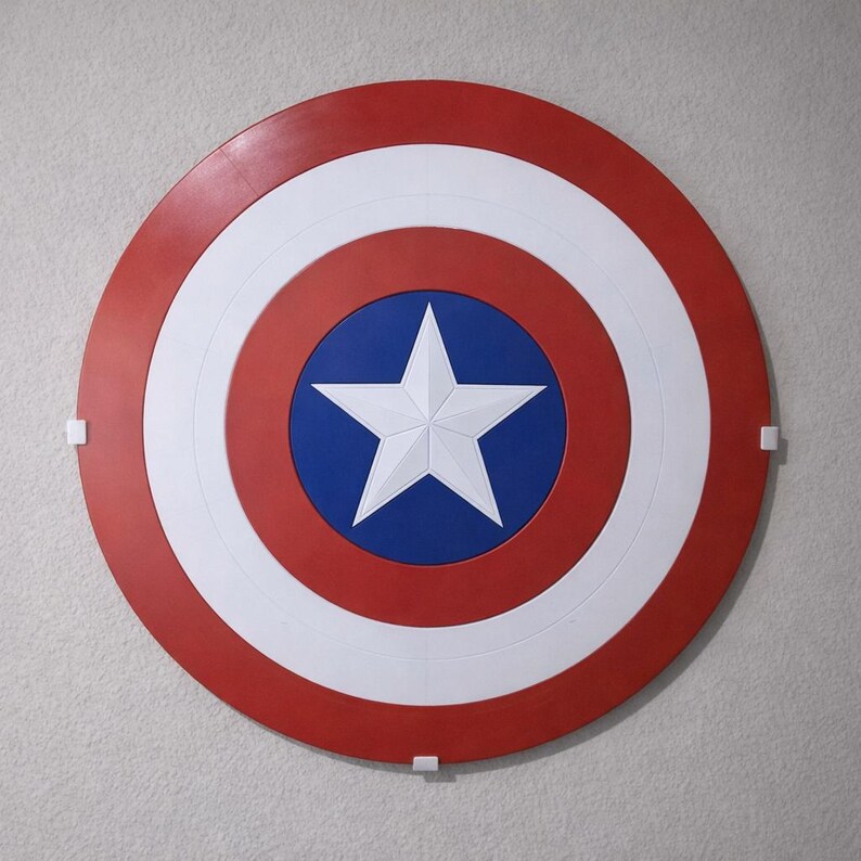 May include: A circular shield with a red outer ring, a white middle ring, and a blue center. A white five-pointed star is in the center. The shield is mounted on a light gray wall.
