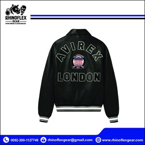 May include: A black leather jacket featuring the white embroidered text AVIREX and LONDON on the back. A circular patch in the centre displays an American flag design with the text ALL AMERICANS ESTABLISHED 1975. The jacket has striped cuffs.