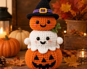 May include: A stacked crochet amigurumi decoration featuring a bottom orange jack-o'-lantern, a middle white ghost, and a top orange pumpkin wearing a black witch hat with a purple band and yellow buckle, all with black eyes and stitched smiles.
