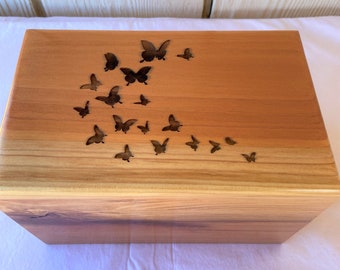 Puede incluir: Una caja de madera con un acabado de madera natural y una tapa con un diseño de varias mariposas cortadas en la madera.