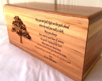 Puede incluir: Una caja de madera con un árbol grabado con láser y un poema sobre encontrar la luz en tiempos oscuros. El poema dice: "Que veas la luz de Dios en el camino que se abre ante ti cuando el camino que recorres es oscuro. Que siempre escuches, incluso en tu hora de dolor, el suave canto de la alondra. Cuando los tiempos son difíciles, que la dureza nunca convierta tu corazón en piedra, recuerda siempre cuando las sombras caen que no caminas solo."