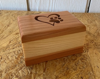 May include: A small wooden box with a heart and paw print design. The box is made of cedar wood and has a natural finish.