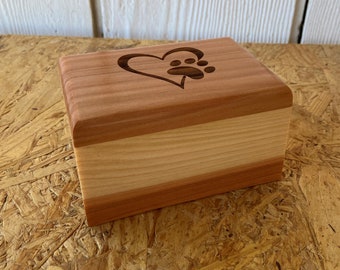 May include: A small wooden box with a heart and paw print design. The box is made of cedar wood and has a natural finish.