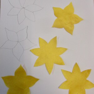 May include: Five yellow felt flower appliques, ready to iron and stitch down.  Two outlined flower shapes are also shown.