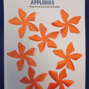 May include: Seven orange felt appliques in the shape of a flower with six petals. The appliques are 3.25 inches wide and are ready to iron in place and stitch down.