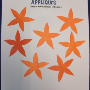 May include: Seven orange felt flower appliques, ready to iron and stitch down. The appliques are in the shape of a five-pointed star with rounded edges. The text "APPLIQUES" is printed in blue at the top of the white card.