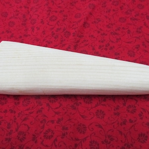 May include: A plain, unfinished wooden dowel with a rounded end. The dowel is light brown in color and has a smooth surface.