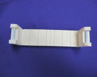 May include: A wooden soap mold with adjustable dividers. The mold is made of light wood and has two metal screws on the sides.