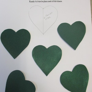 May include: Five green felt heart appliques, each measuring 2.5 inches by 2.5 inches. The appliques are ready to be ironed and stitched onto fabric.
