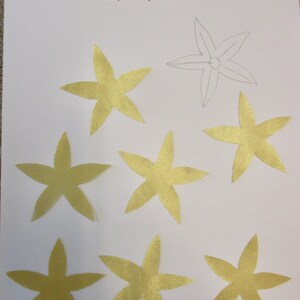 May include: Eight gold star-shaped fabric appliques, ready to be ironed and stitched onto a project. The appliques are on a white background.