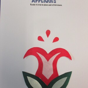 May include: Red and pink flower applique with green leaves. The applique is ready to iron in place and stitch down.  "Appliques" is written in blue letters at the top of the page.