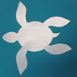 May include: A white paper cutout of a turtle on a teal blue background.