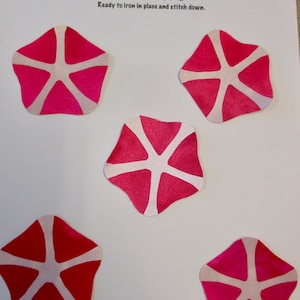 May include: Five pink and white appliqués in a starburst design. The appliqués are ready to iron in place and stitch down. The text "Creations by Melodie" and "APPLIQUÉS" are visible.