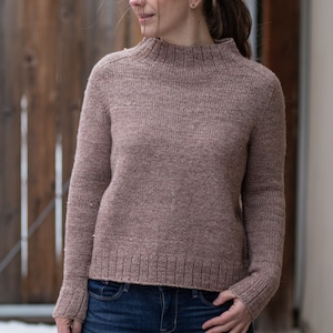 Op de afbeelding: Een bruine, lange mouwen trui met een mock neck en een geribbelde zoom.